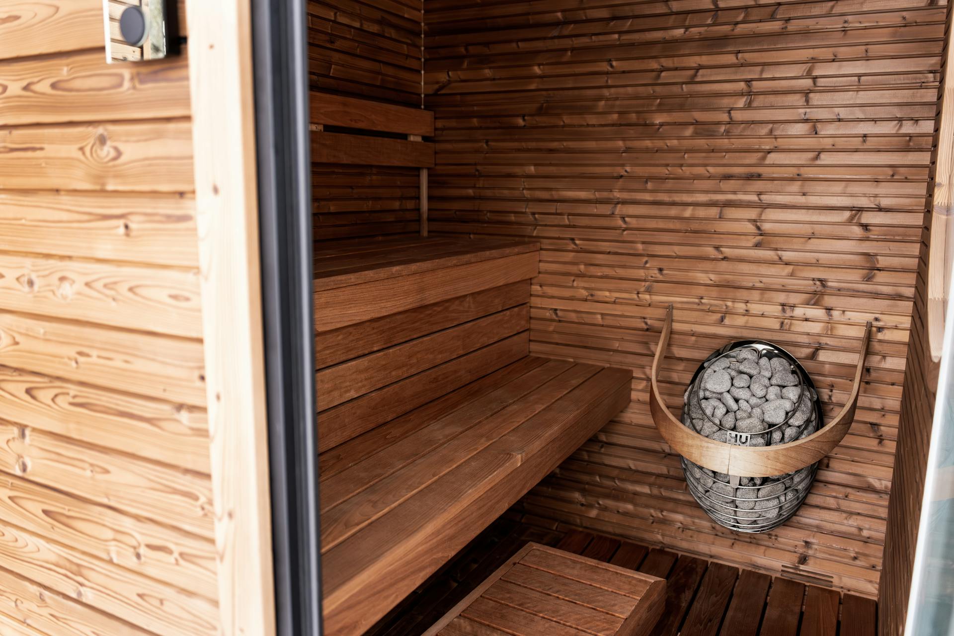 A warm cedar sauna lit by a stone heater — Sauna & Cold Plunge